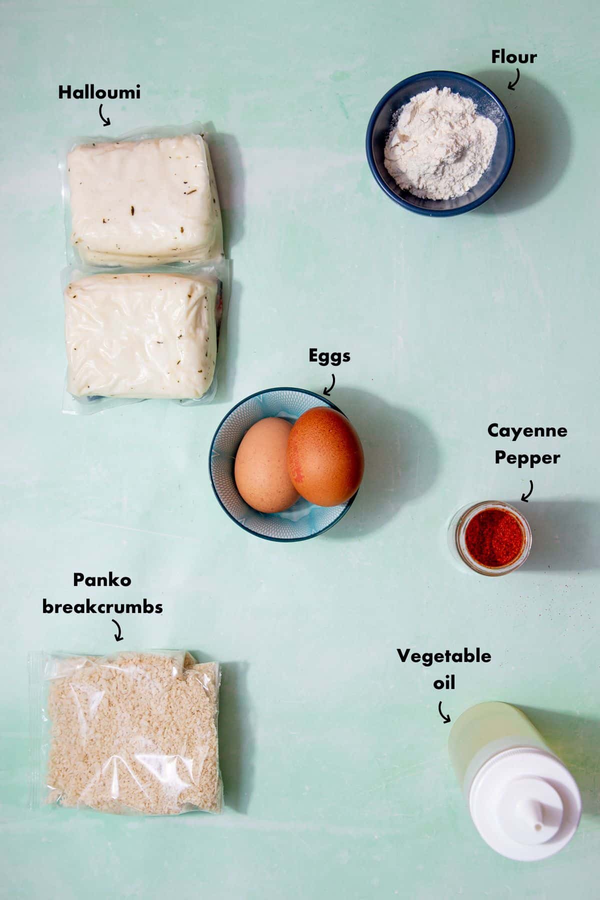 Ingredients to make halloumi fries laid out on a pale blue background and labelled.