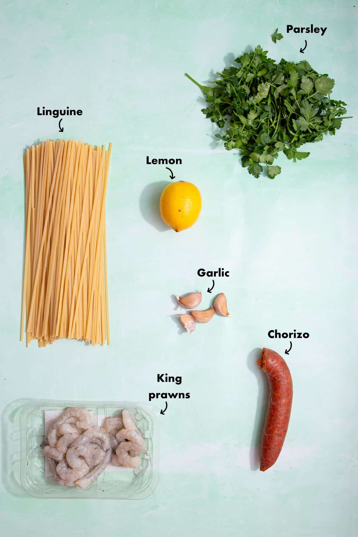Ingredients to make prawns with chorizo and linguine laid out on a pale blue background and labelled.
