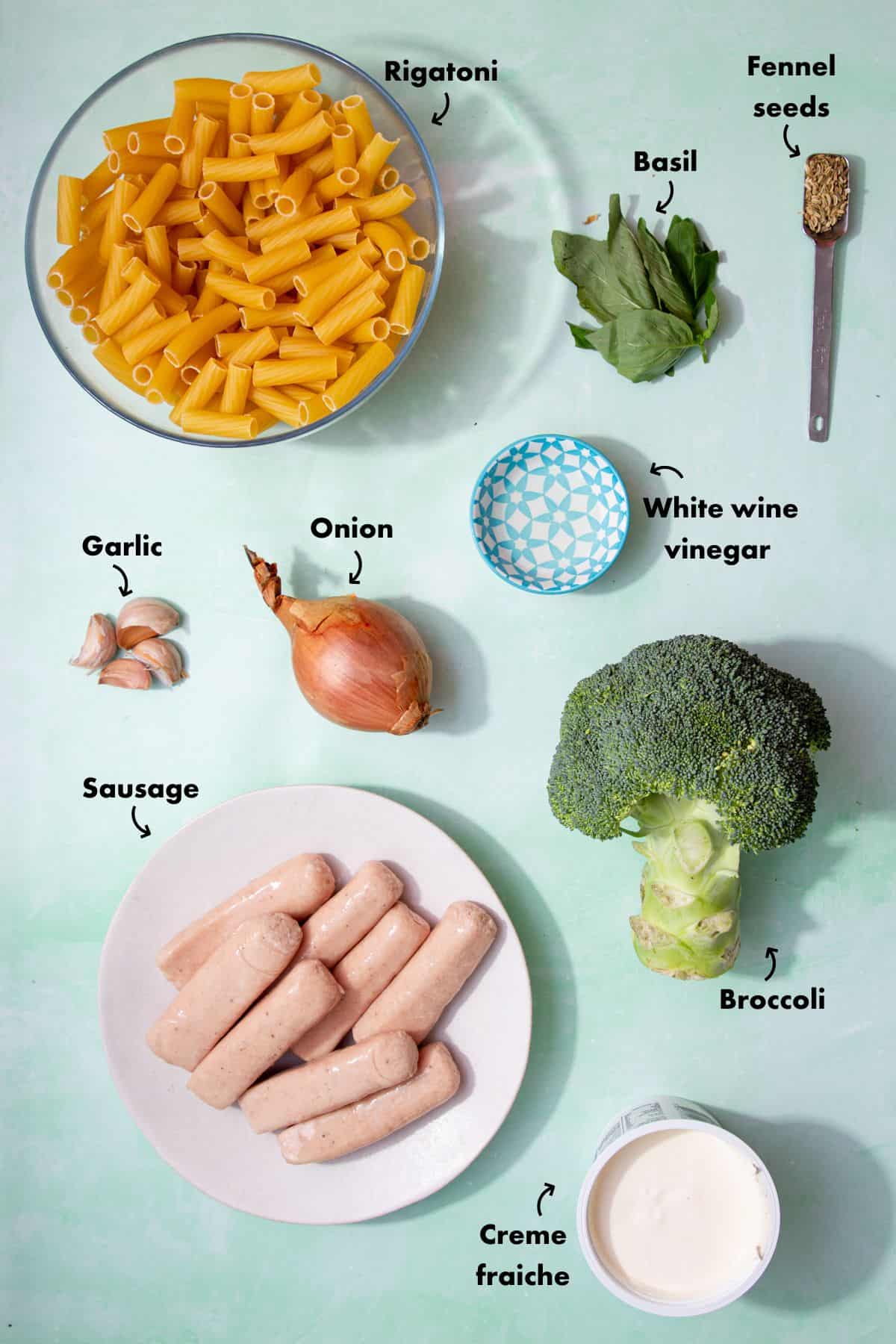 Ingredients to make the cream sausage pasta laid out on a pale blue background.