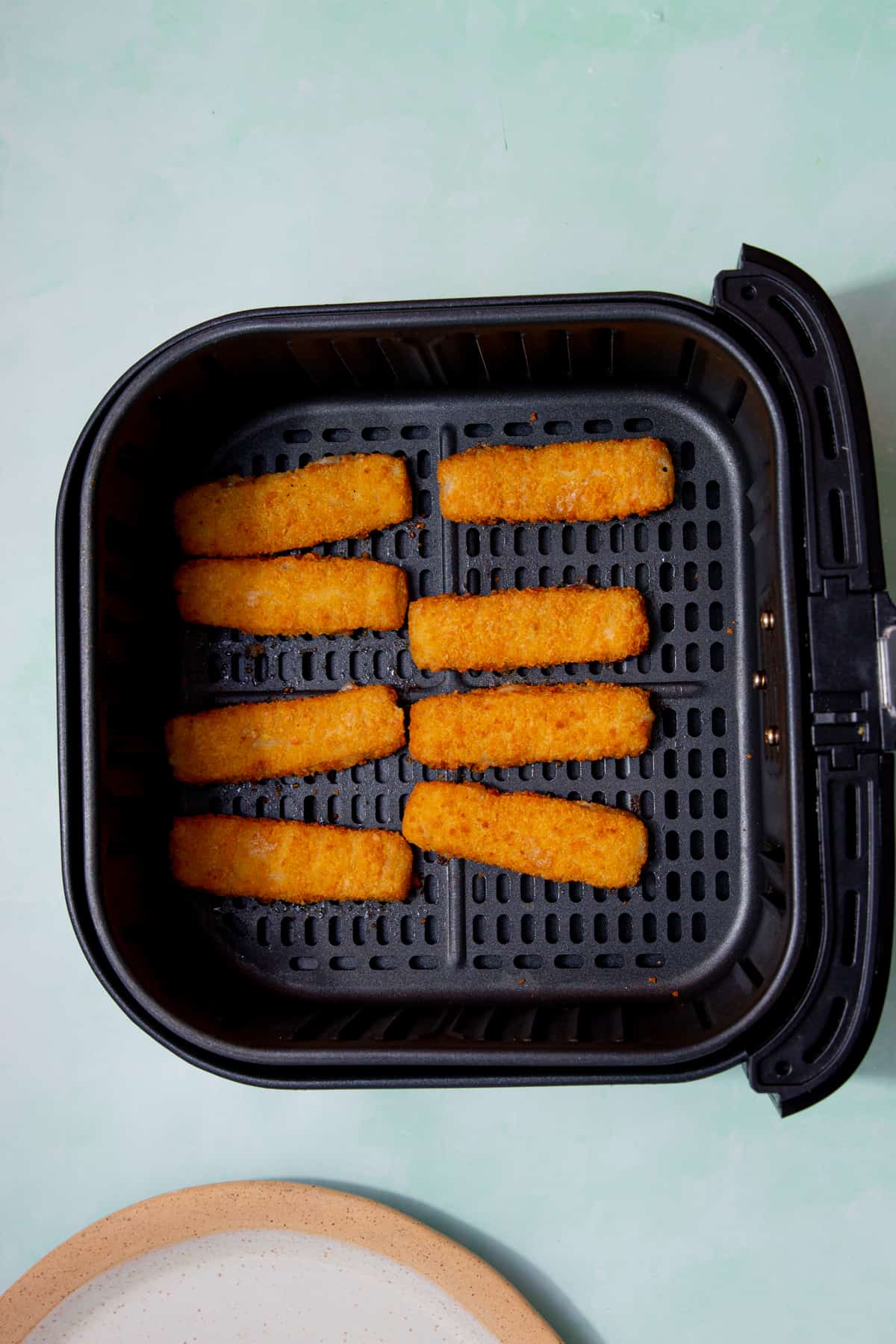 8 battered fish fingers in the airfryer tray.