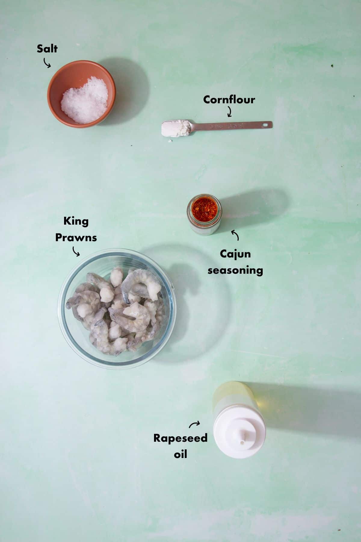Ingredients to make the king prawn recipe laid out on a pale blue background and labelled.