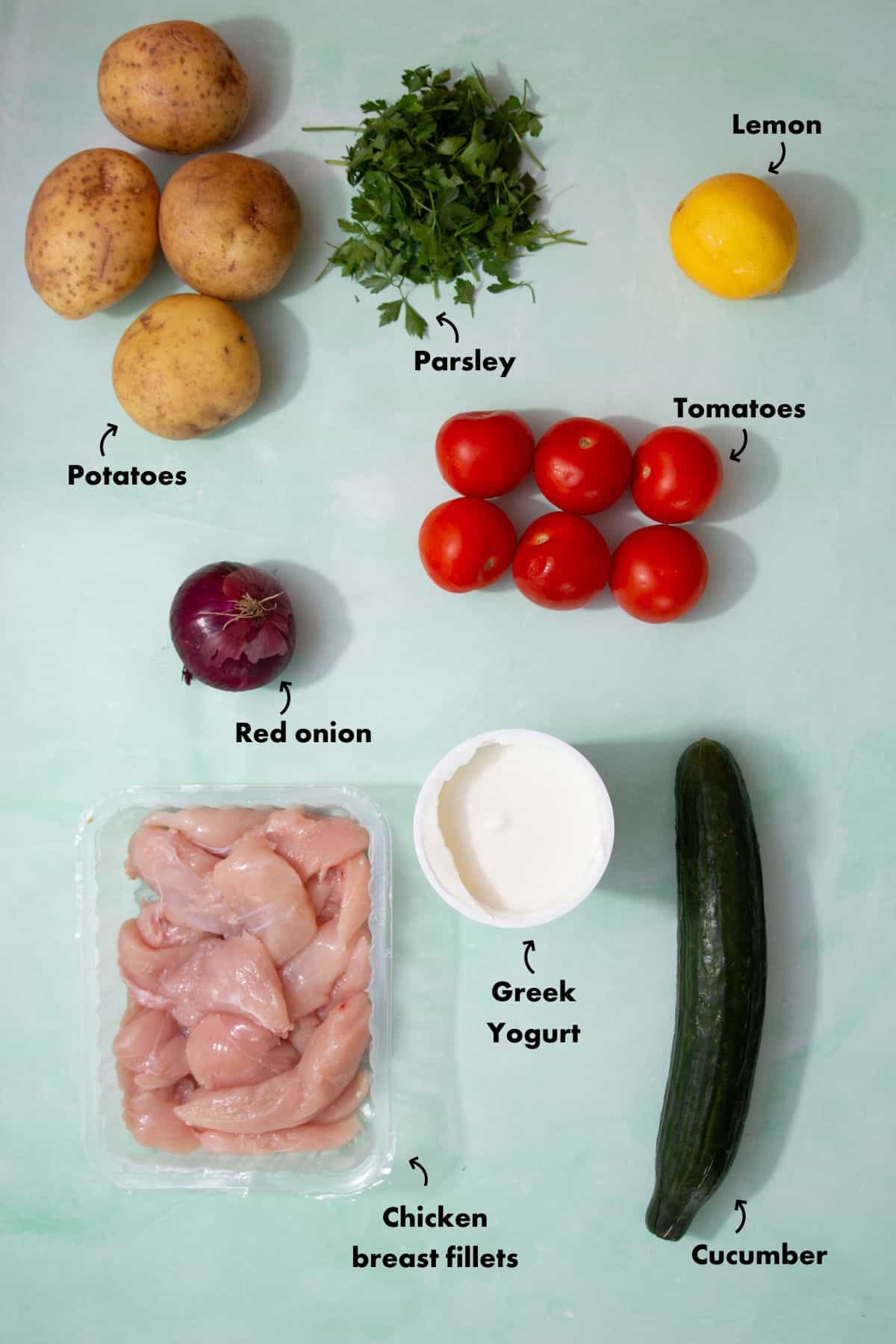 Ingredients to make chicken salad bowls laid out on a pale blue background and labelled.