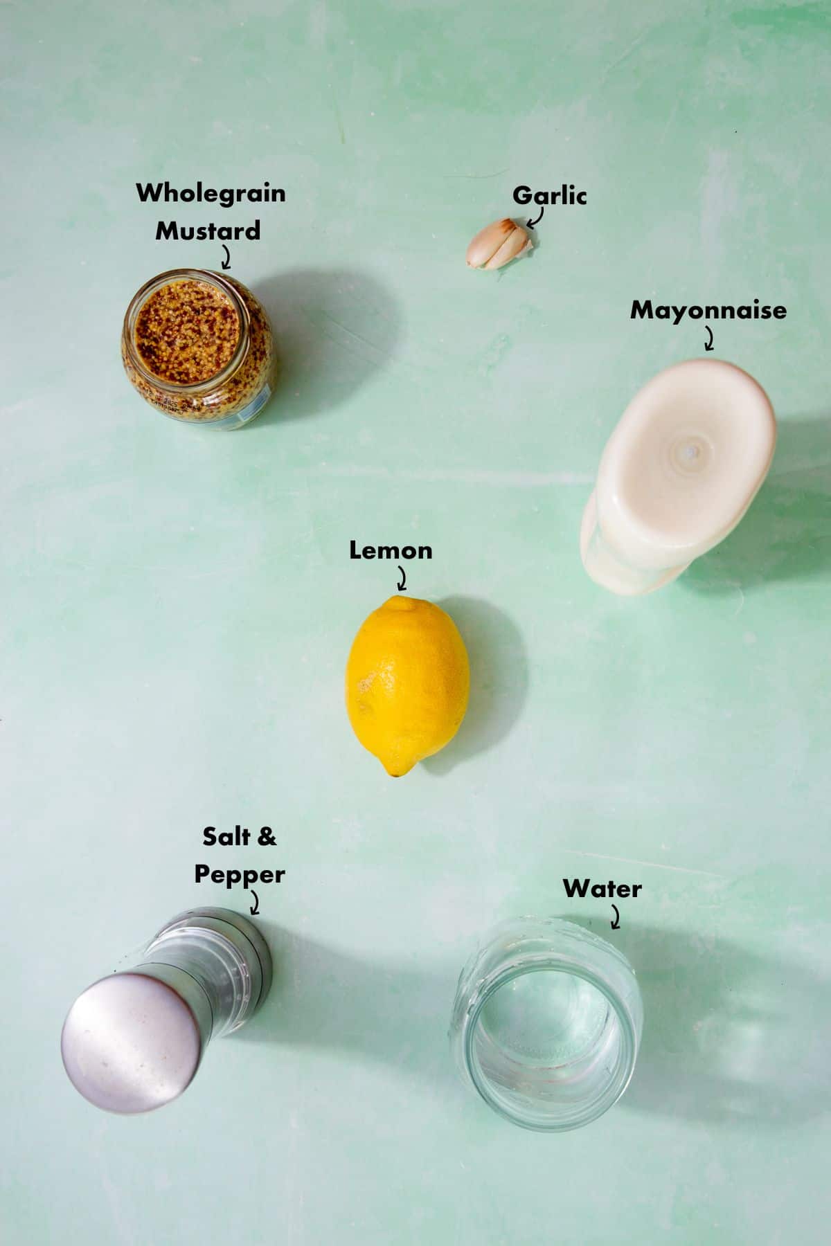 Ingredients to make the salad dressing laid out on a pale blue background and labelled.