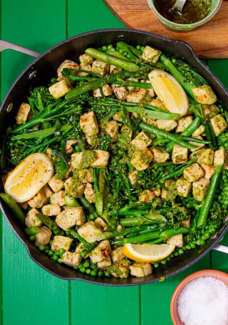 A lagre pan with pieces of quorn with broccoli and beans topped with some lemon wedges.