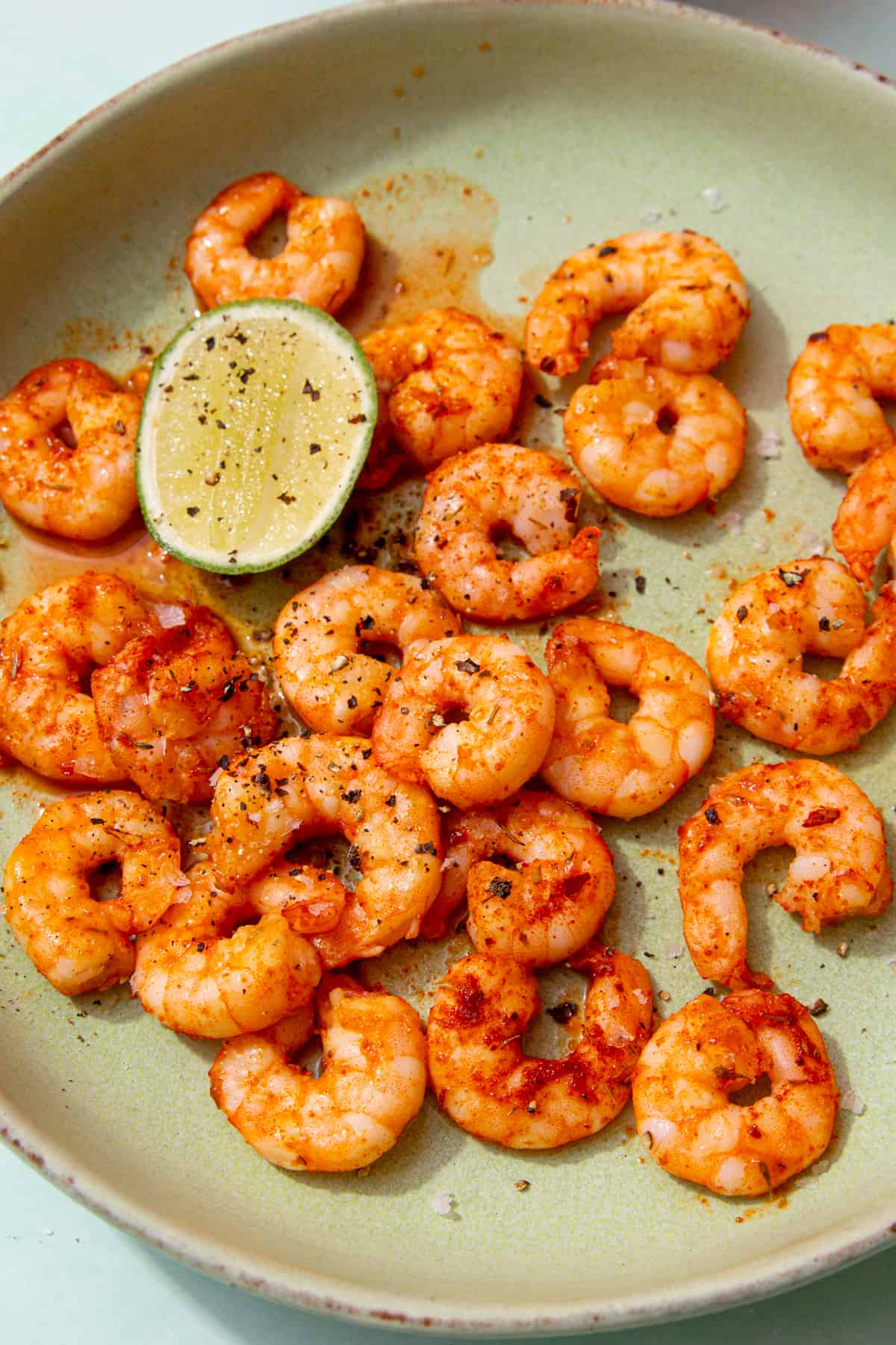 Seasoned King prawns in a bowl with half a lime wedge and topped with extra seasoning.