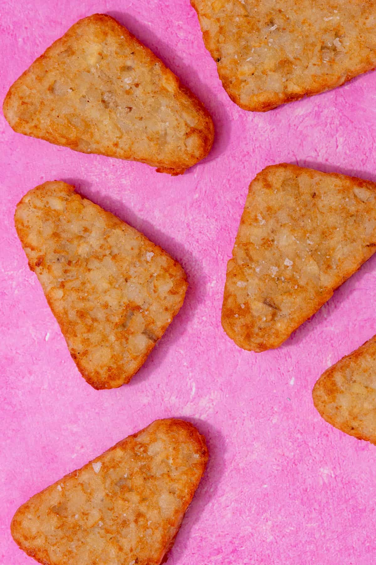 Frozen hash browns laid out on a pink background.
