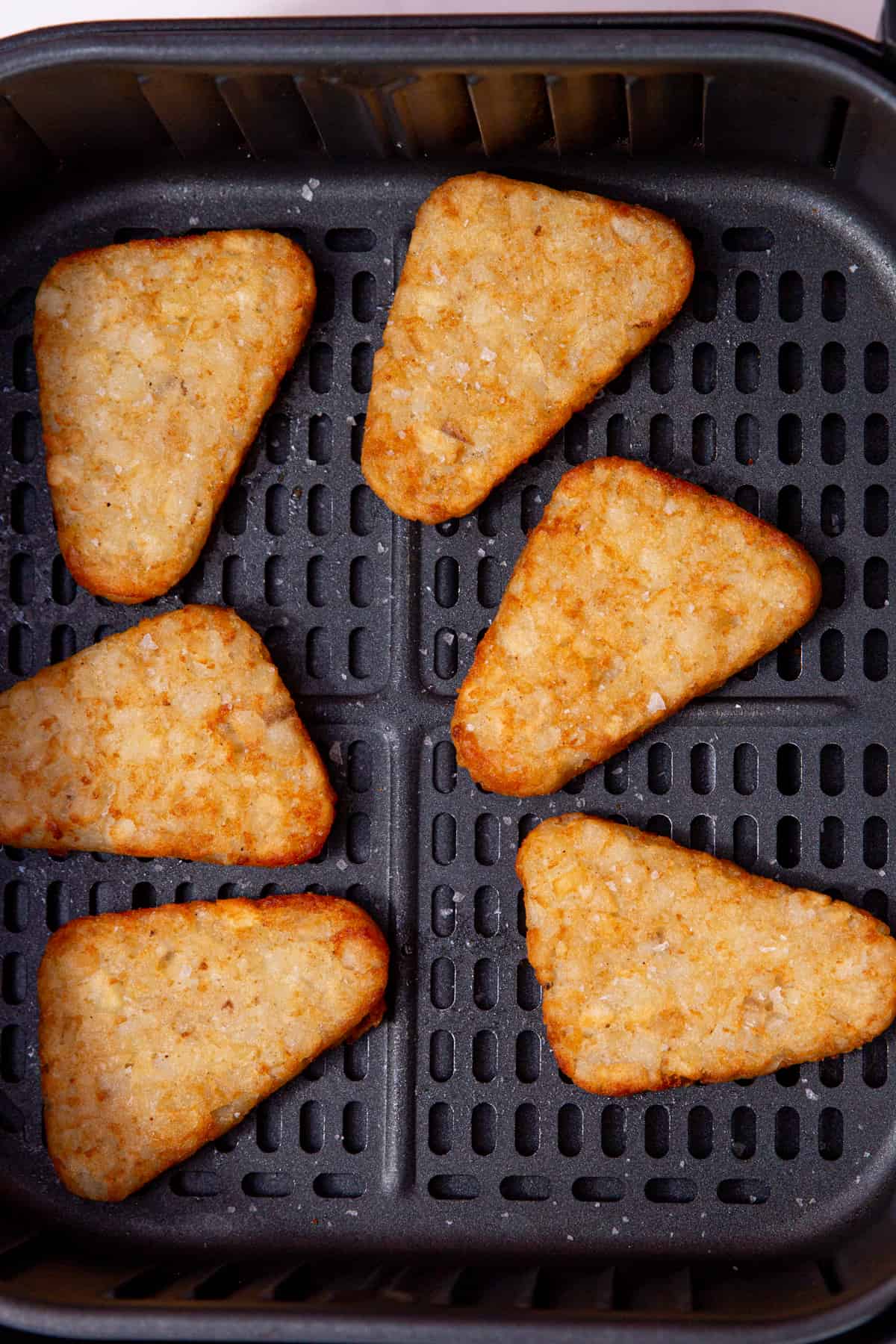6 cooked hash browns in the airfryer tray with a sprinkle of salt.