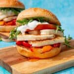 2 halloumi burger with lots of filling including tomatoes, lettuce, tzatziki and roasted peppers topped with a sesame bun.