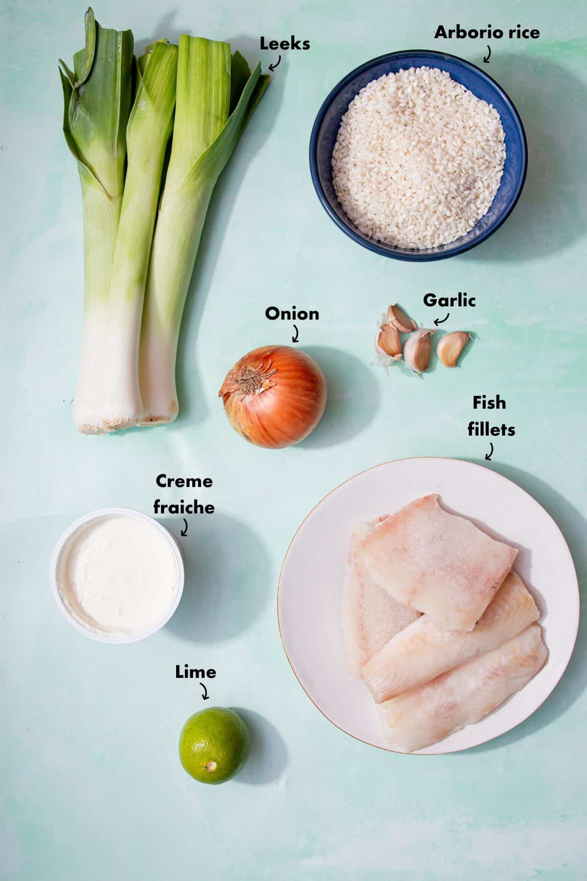 Ingredients to make the fish risotto laid out on a pale blue background and labelled.