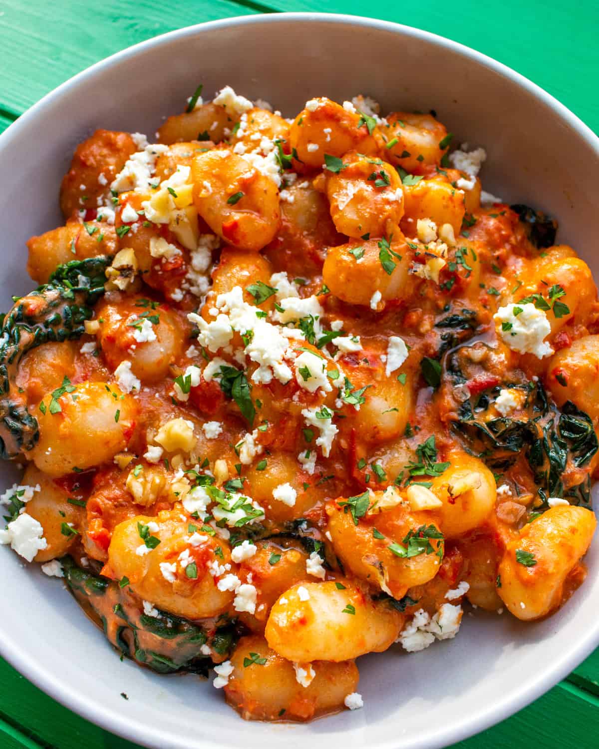 Gnocchi with a tomatoey sauce with some sprinkles of cheese and herbs in a bowl.