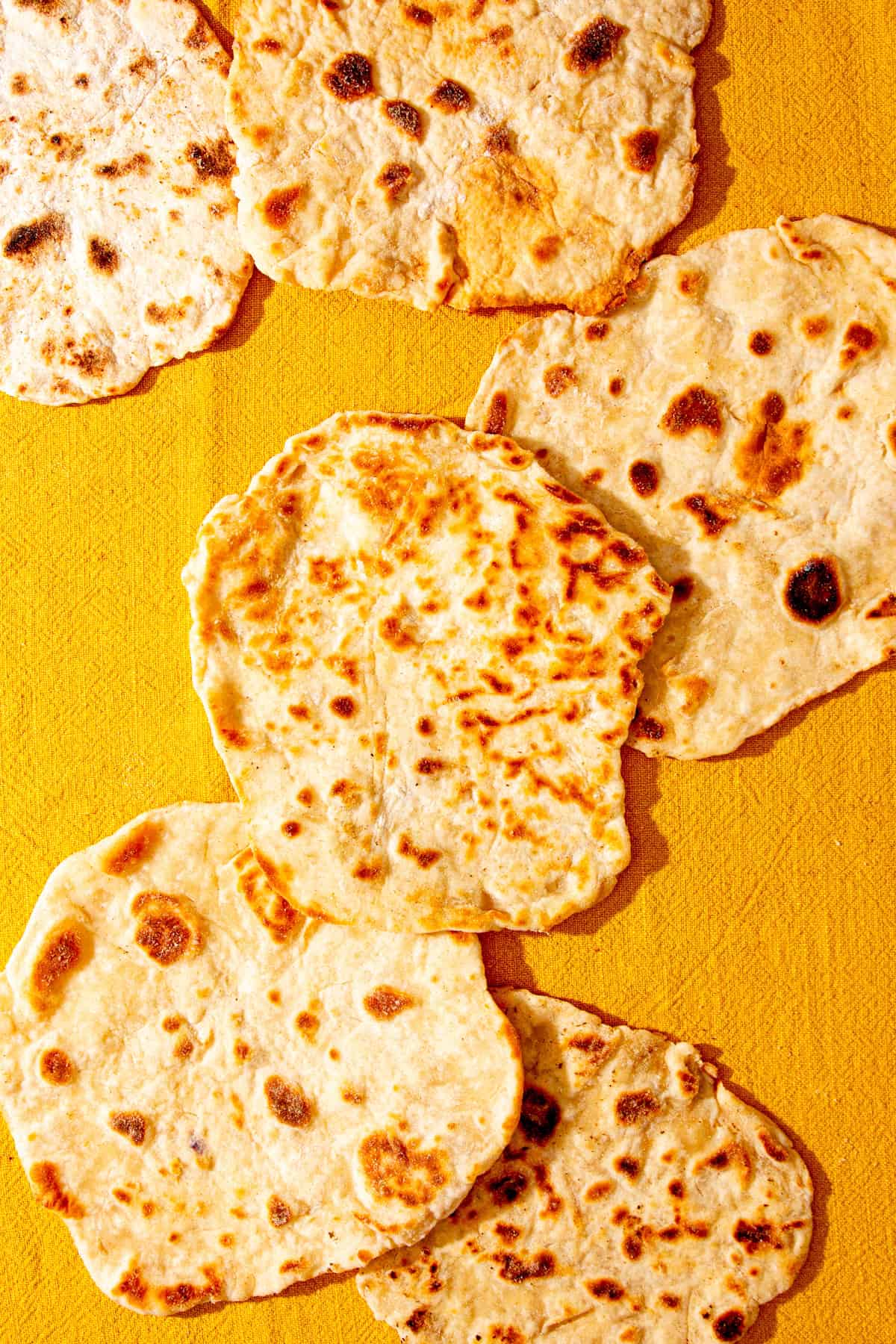 Golden browned flatbreads on a yellowy coloured cloth.
