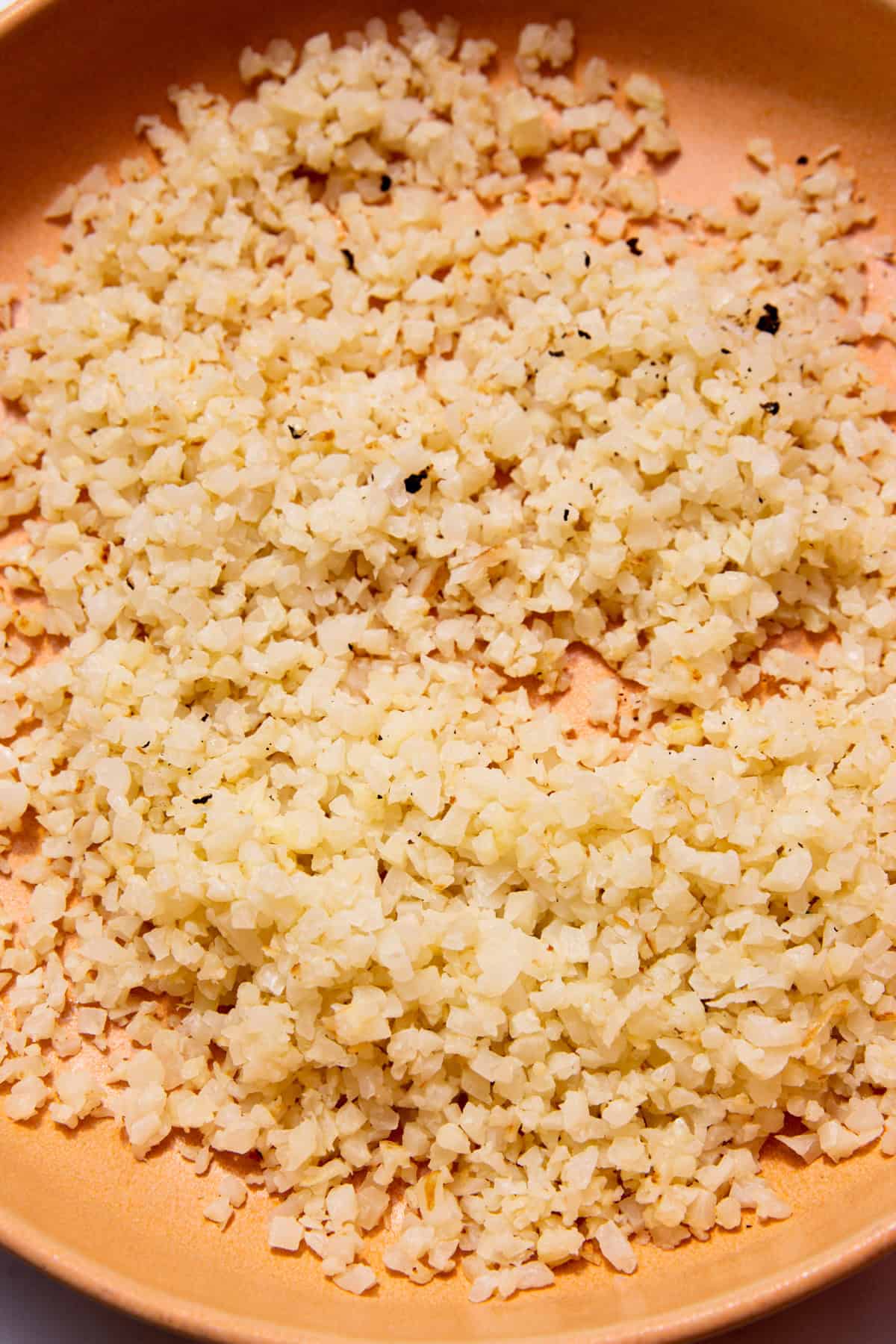 A pale tanned coloured bowl with cauliflower rice.