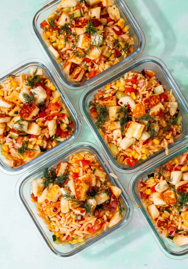 5 square glass meal pprep containers with orzo pasta salad with halloumi topped with some dill.