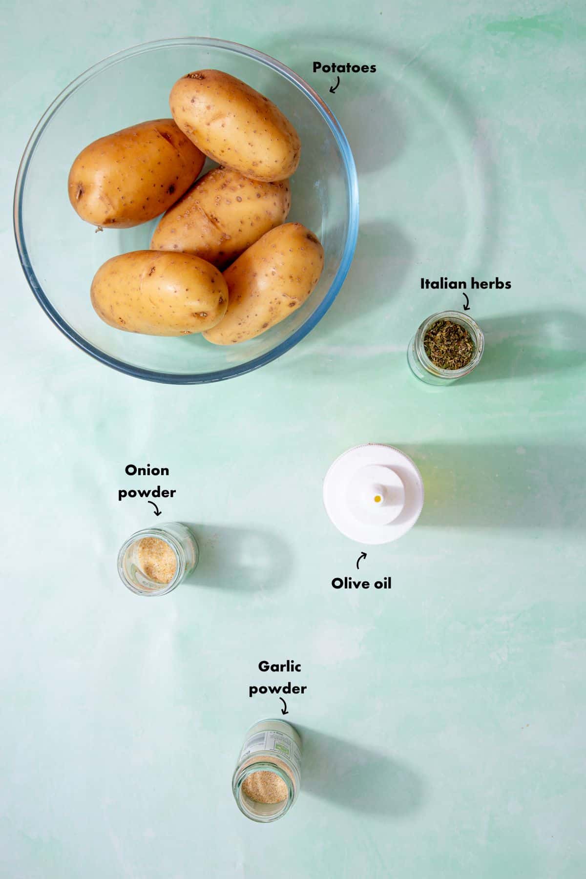 Ingredients to make the Air Fryer potatoes recipe laid out on a pale blue background and labelled.