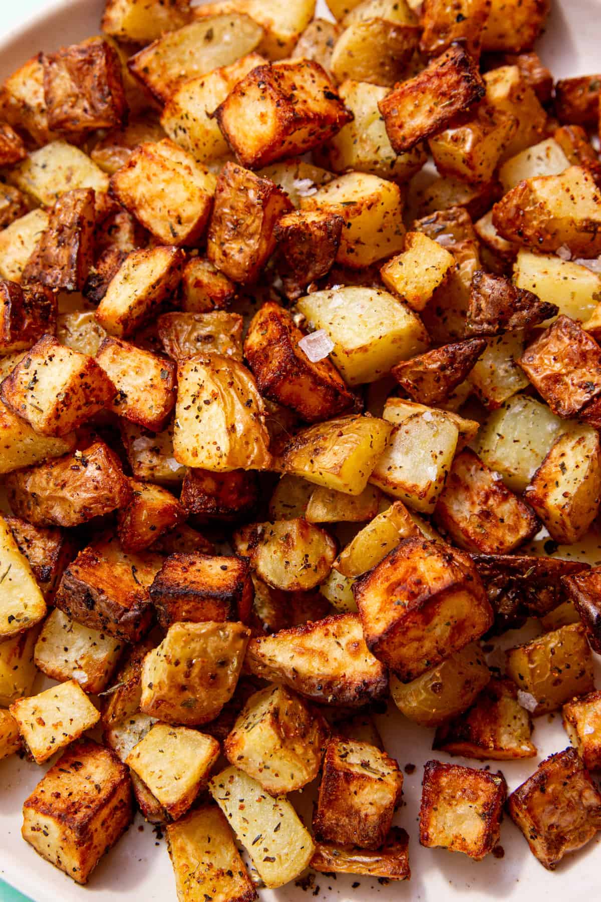 Golden browned diced potatoes with some salt sprinnkled over them on a plate.