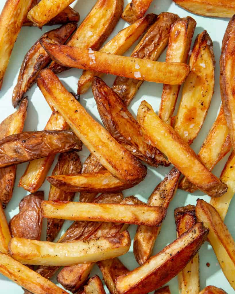 Golden browned baked potato chips on a pale blue background.