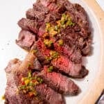 Slices of cooked rib eye steak, some medium rare slices in the middle and some dressing poured overdrizzled over the middle of the steak slices