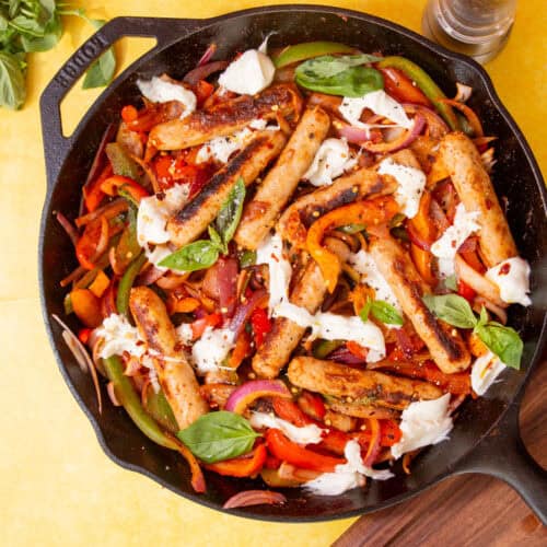 A harge skillet pan with Golden browned sausages, peppers, onion and mozarella cheese topped with fresh basil.