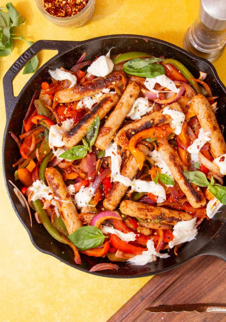 A harge skillet pan with Golden browned sausages, peppers, onion and mozarella cheese topped with fresh basil.