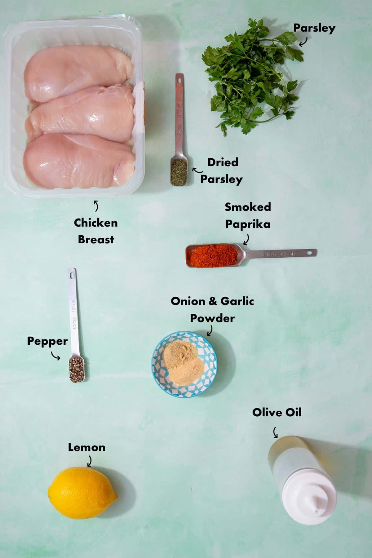 Ingredients to make the chicken recipe in the oven laid out on a pale blue background and labelled.