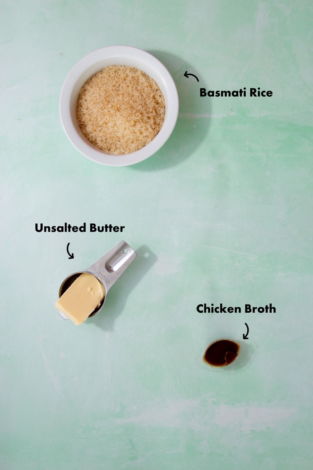 Ingredients to make the rice with chicken broth on the stove laid out on a pale blue background and labeled with arrows.