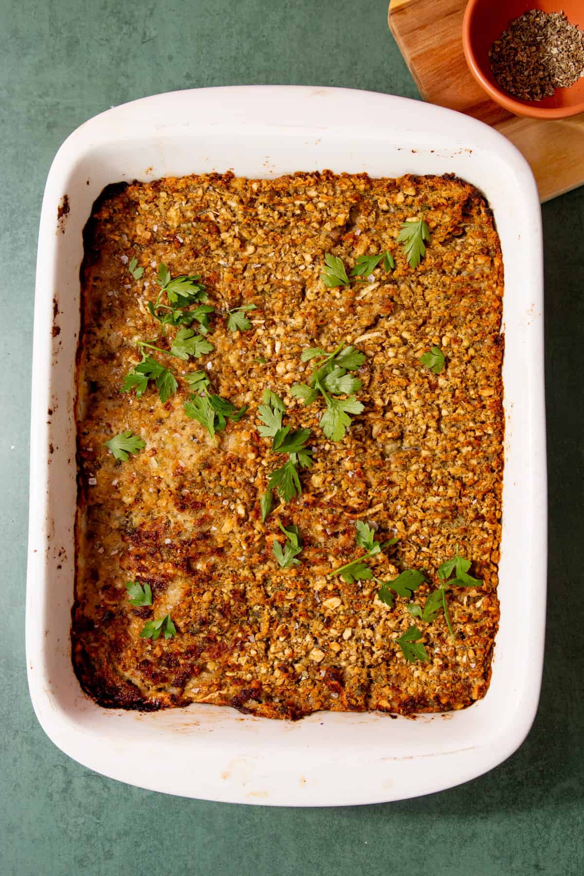 baked sausage meat stuffing in a white baking dish and topped with fresh parsley.