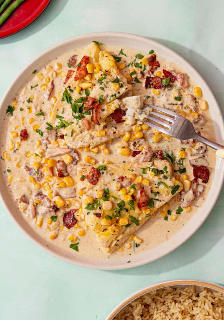 feature image of smoked haddock recipe served with a creamy sauce, corn, bacon, and topped with parsley.