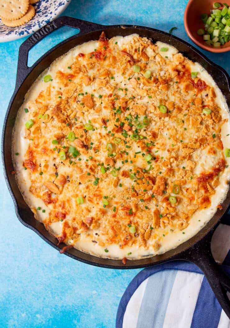 image of baked million dollar chicken casserole in a cast iron skillet on a blue background