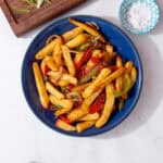 salt and pepper chips feature image containing chips with onions, peppers, salt and pepper in a blue bowl.