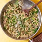tuna pesto pasta in stainless steel skillet on a yellow background