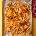 animal style fries cooked in an oven on a baking sheet on a yellow background