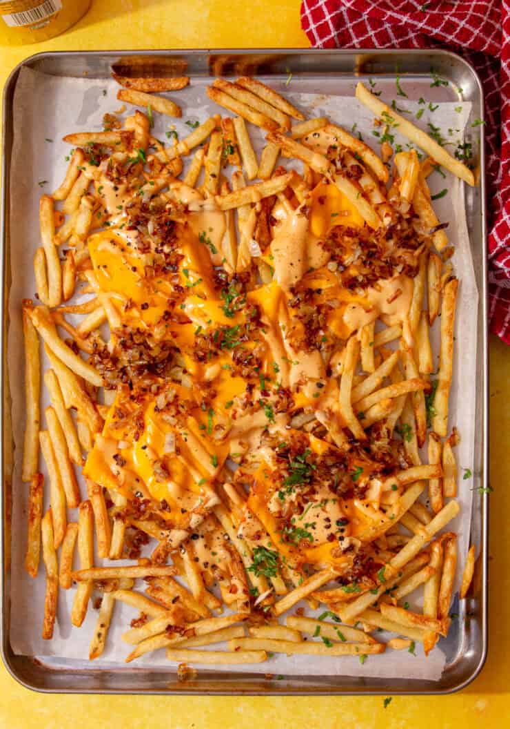 animal style fries cooked in an oven on a baking sheet on a yellow background