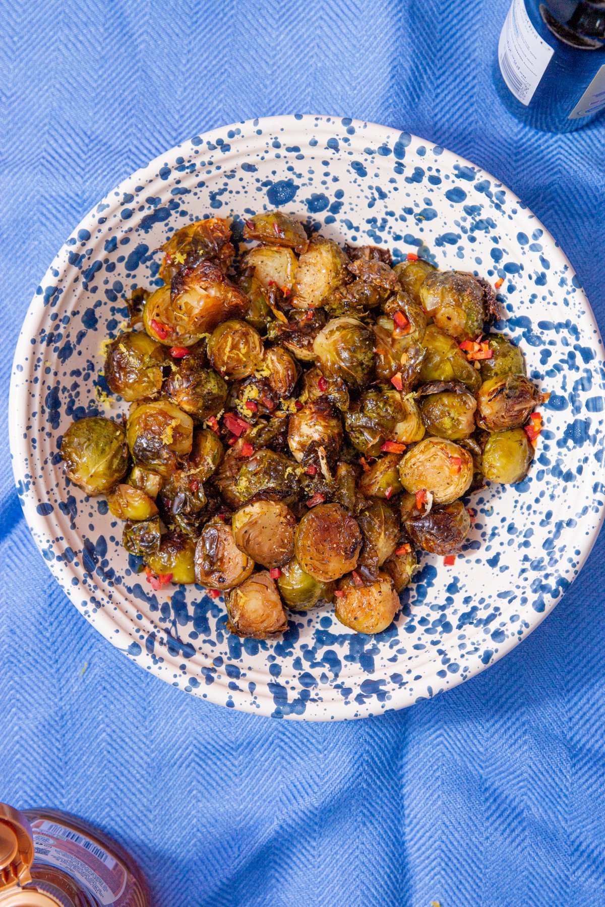 honey balsamic brussel sprouts in a blue and white speckled bowl on a blue background