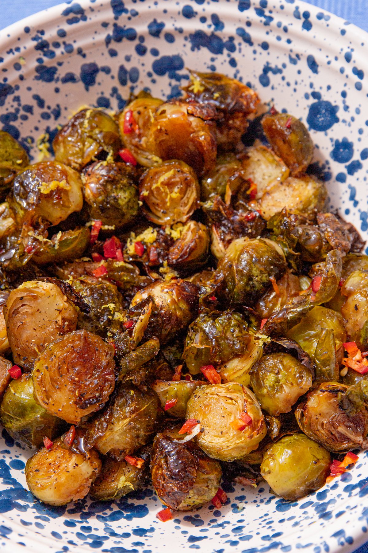 close up of honey balsamic brussel sprouts in a blue and white speckled bowl