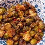 honey balsamic brussel sprouts in a blue and white speckled bowl