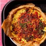 fully cooked air fryer frittata in an air fryer on a pink and white background