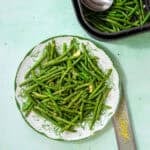 air fryer frozen green beans fully cooked on a white and green plate and a light blue background