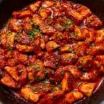 sweet chilli chicken in a black skillet on a yellow background