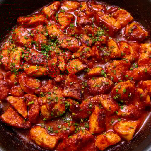 sweet chilli chicken in a black skillet on a yellow background