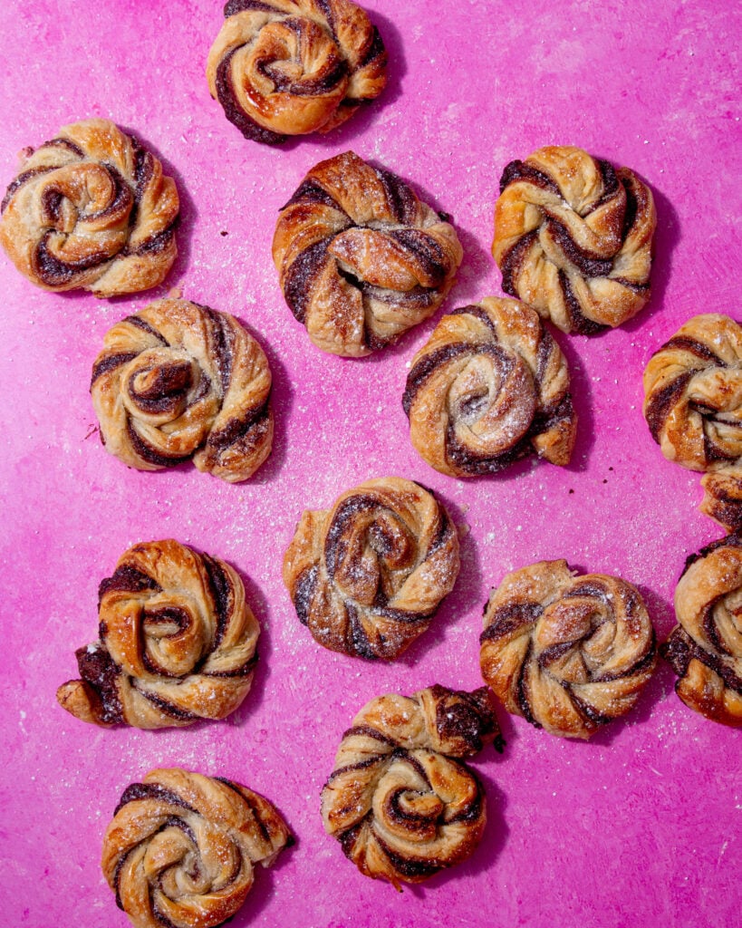 baked nutella puff pastry wheels on a pink background