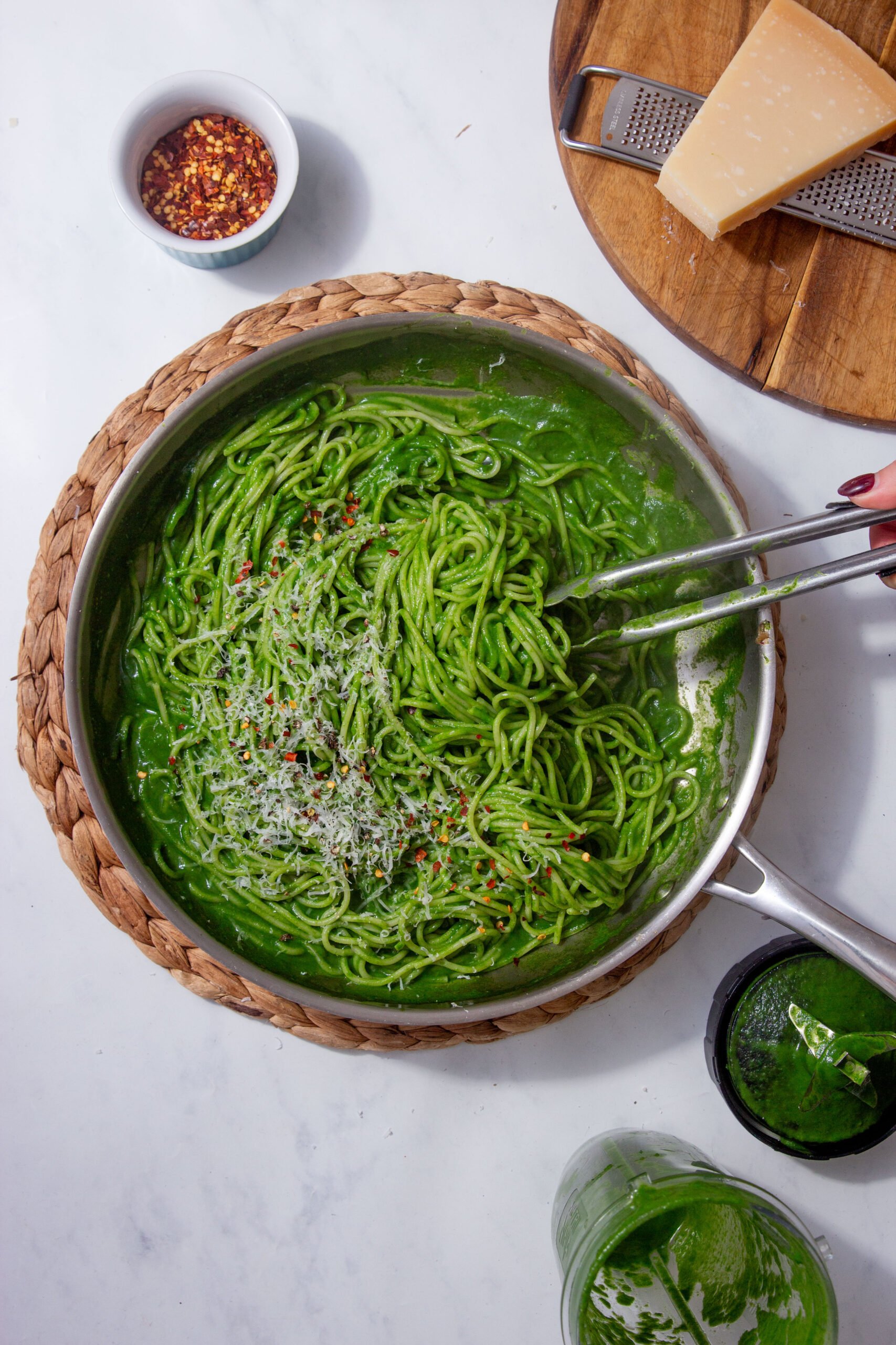 Prepared green spinach pasta sauce served with spaghetti noodles and topped with parmesan cheese and chili flakes.