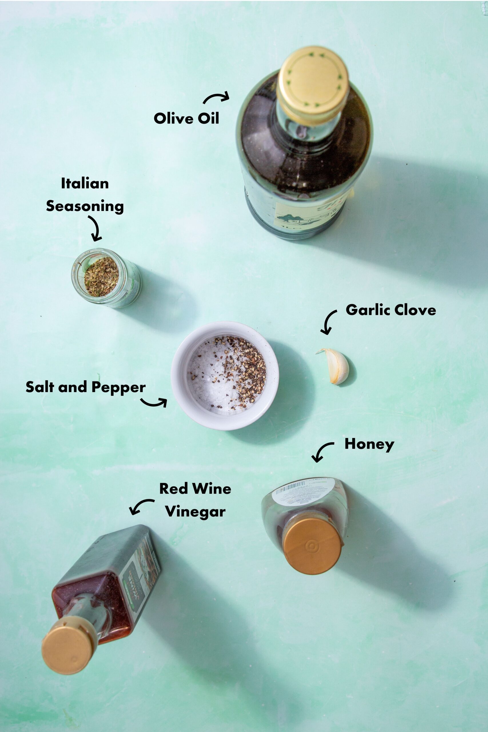 Ingredients to make the submarine dressing in the oven laid out on a pale blue background and labeled with arrows.
