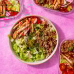 image of prepared burger bowl with other meal prep bowls around it on a pink background