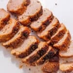 image of perfectly cooked and sliced pork tenderloin in air fryer on a white plate