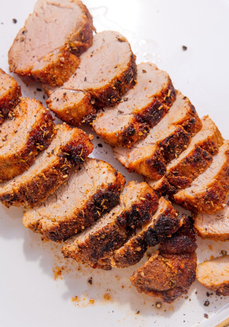 image of perfectly cooked and sliced pork tenderloin in air fryer on a white plate