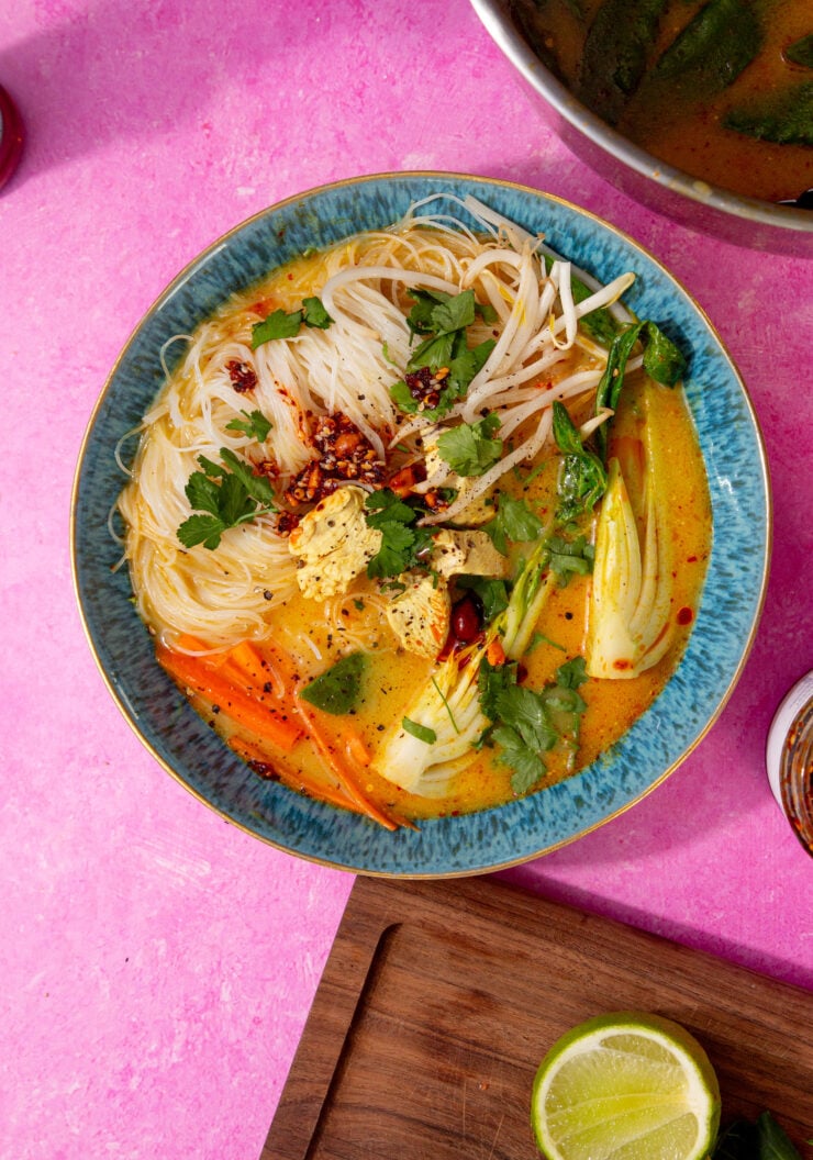 prepared chicken laksa soup in a blue bowl on a purple background