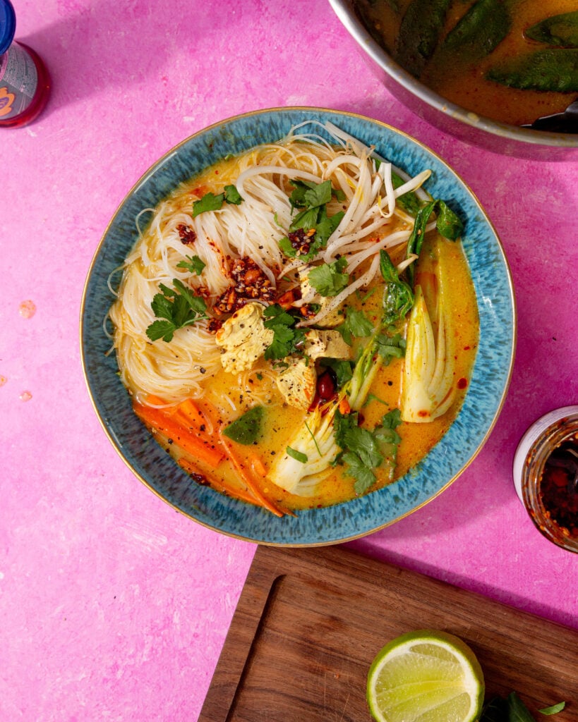prepared chicken laksa soup in a blue bowl on a purple background