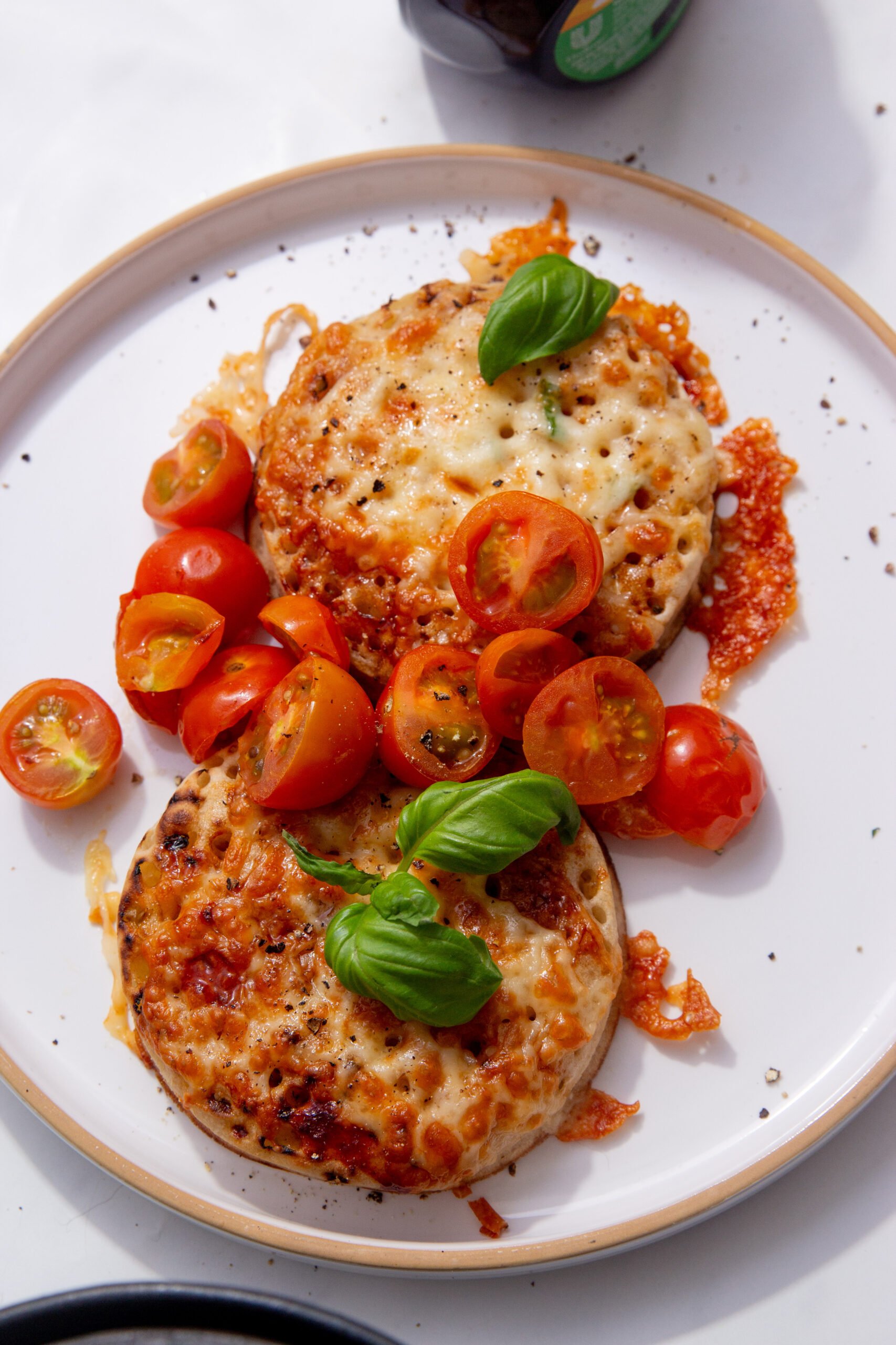 up close image of cheesy crumpets topped with tomatoes and basil.