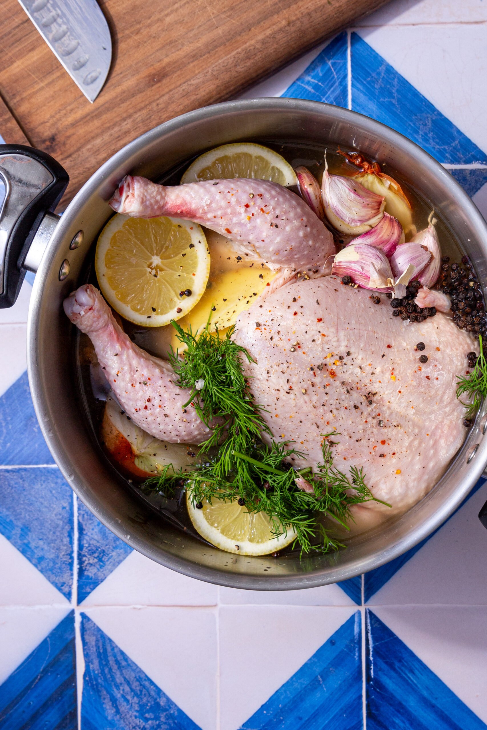 whole chicken in a stock pot with garlic, parsley and lemon slices