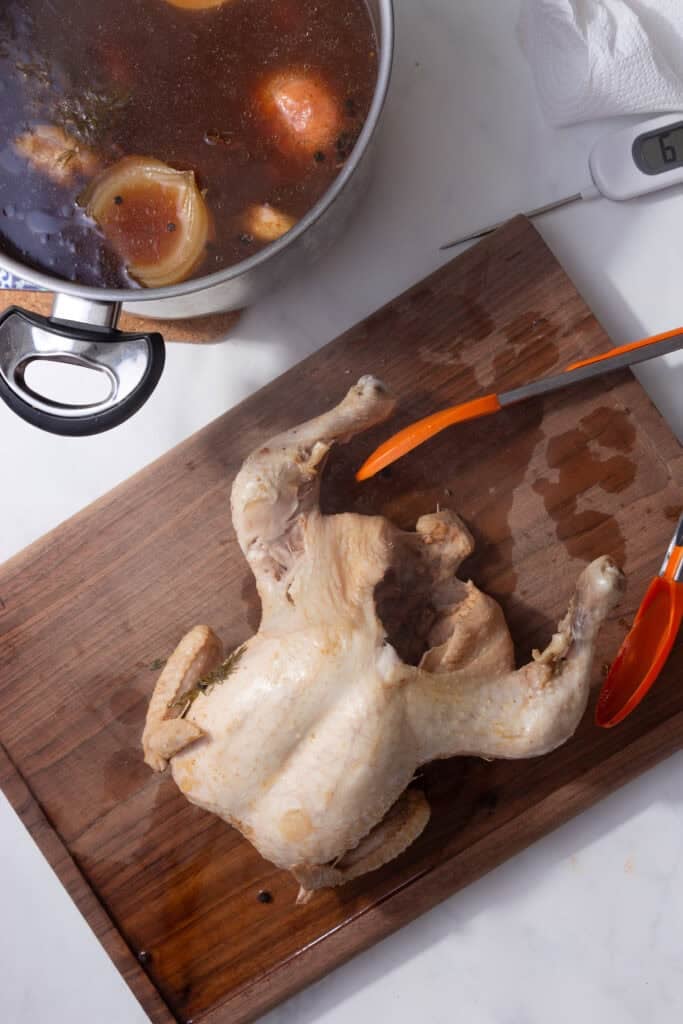 A whole chicken resting on a cutting board. 